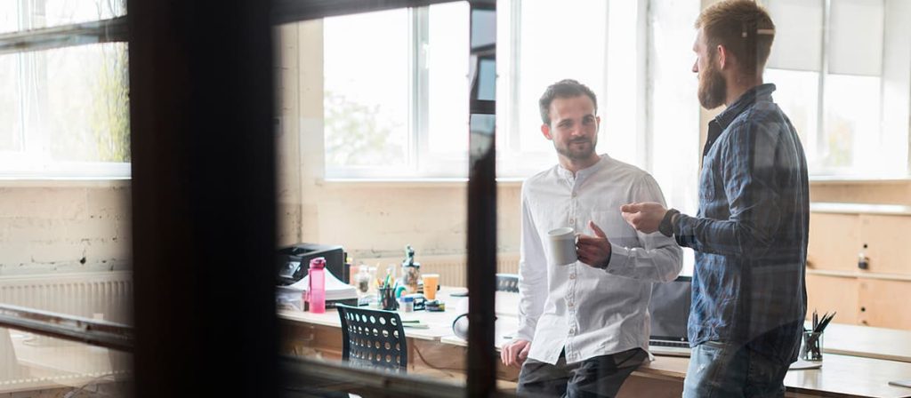 Conversa entre dois homens, ambos estão felizes.